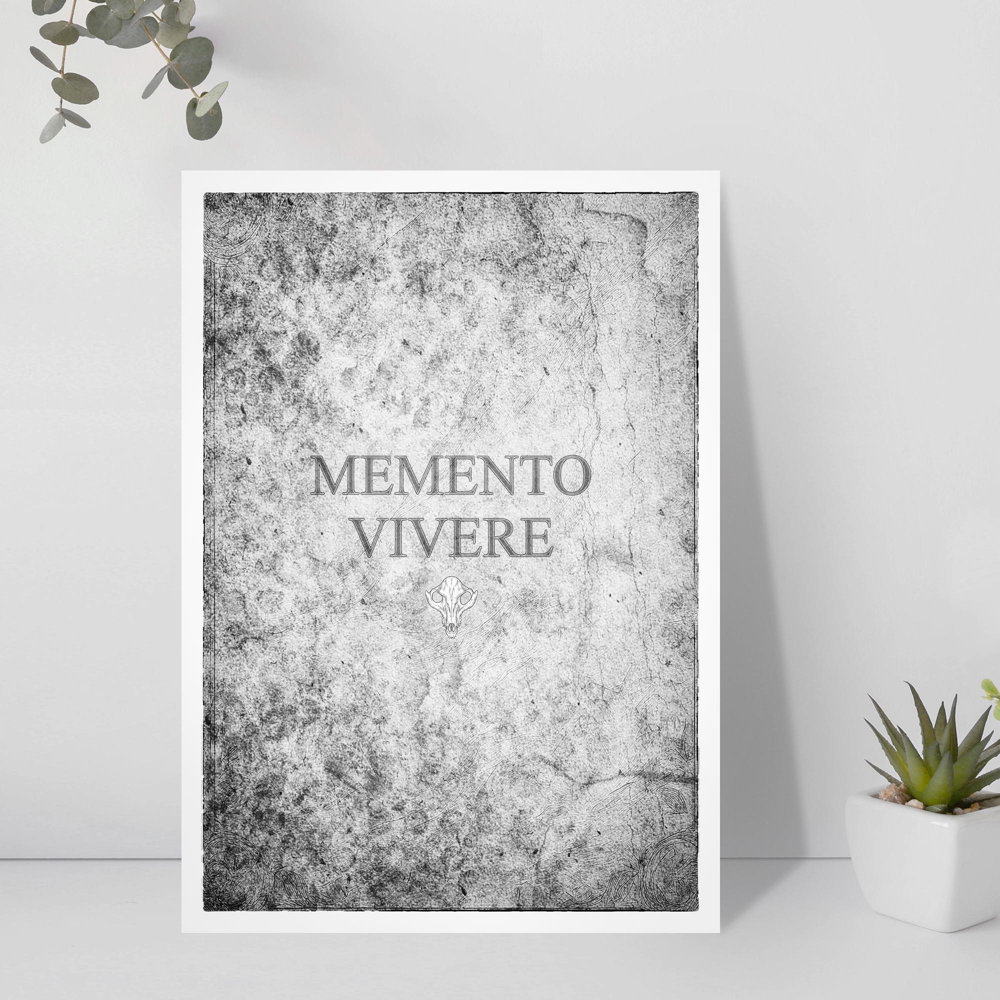 Framed artwork with 'Memento Vivere' text on a textured gray background, placed on a white surface with plants.