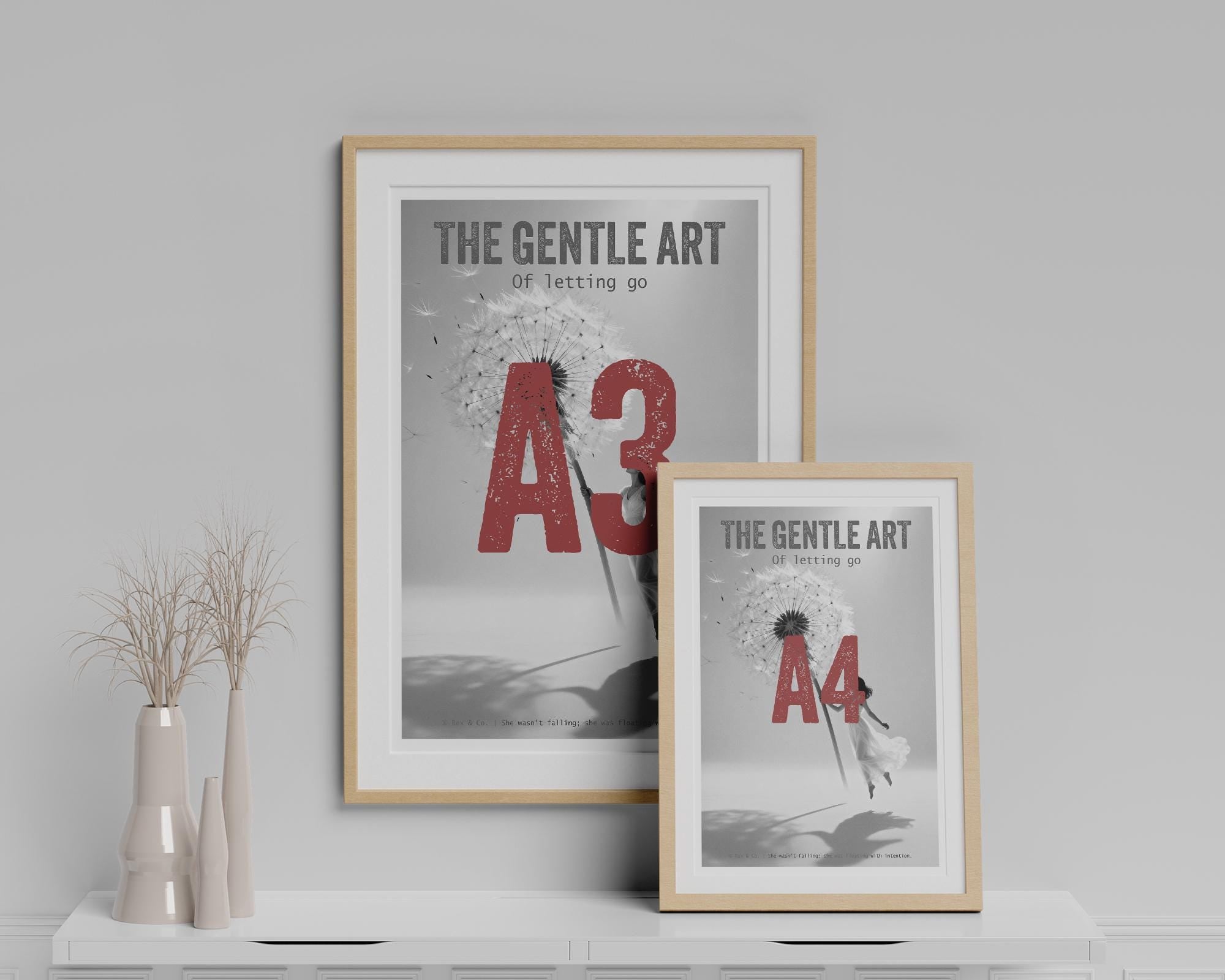 Two framed prints on a shelf with decorative vases against a gray wall.