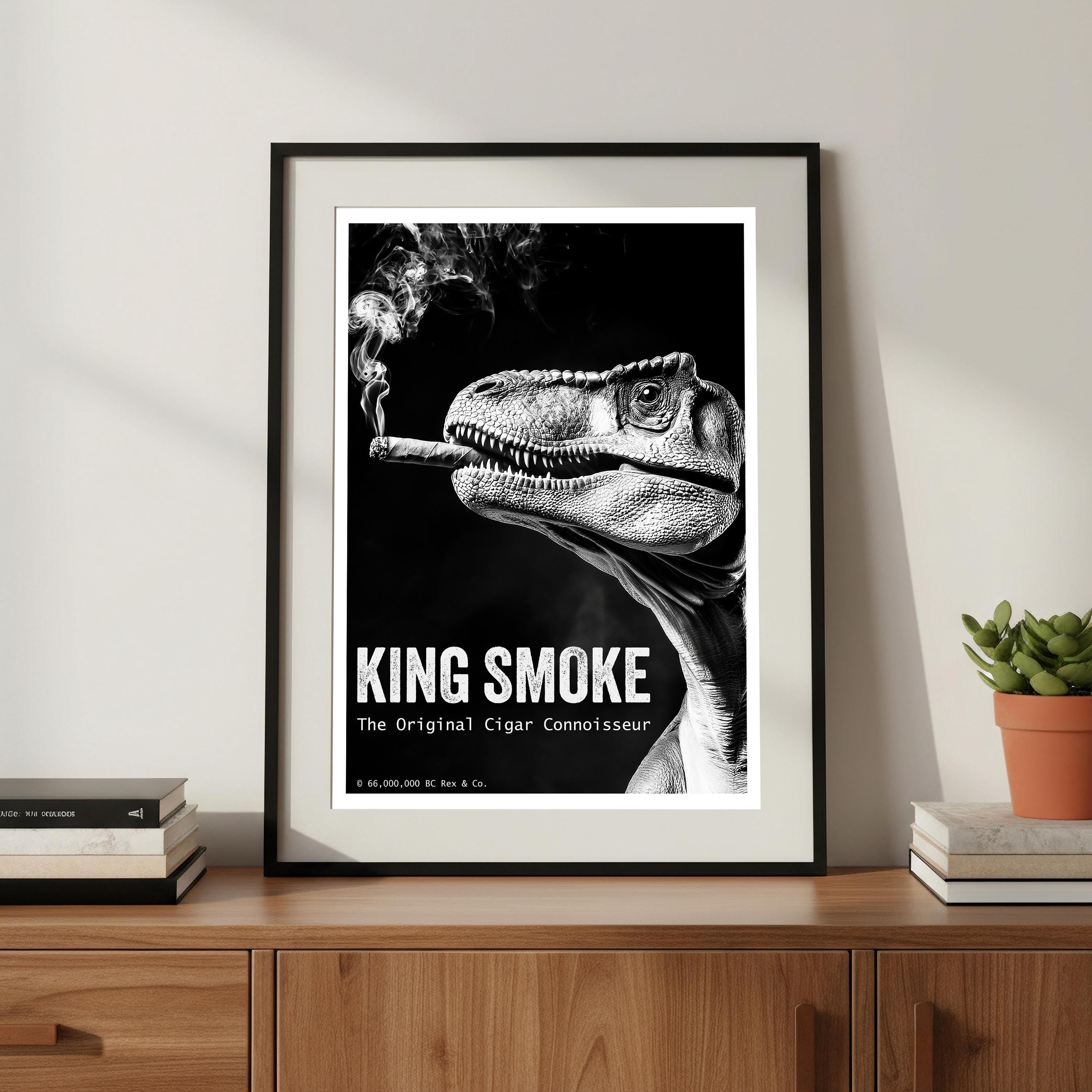 Framed poster of a dinosaur smoking a cigar with 'King Smoke' text on a wooden shelf.