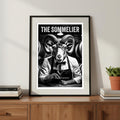 Framed poster of a ram wearing glasses and an apron, titled 'The Sommelier', on a wooden shelf.