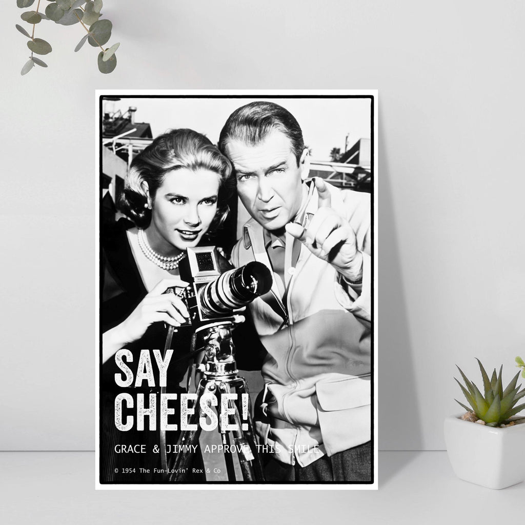 Vintage-style poster of Grace Kelly and James Stewart with a camera, featuring text 'Say Cheese! Grace & Jimmy Approving the View.' on a white background.