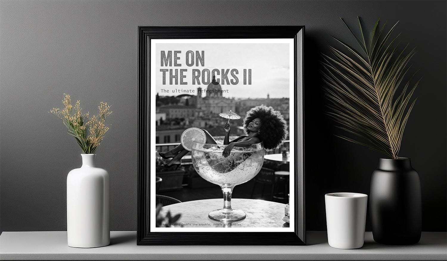 Framed poster of a cocktail with 'Me on the Rocks II' text, displayed on a shelf with decorative items.