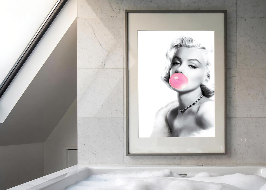 Framed artwork of a stylized portrait of Marilyn Monroe with a pink bubble gum bubble on a marble wall.