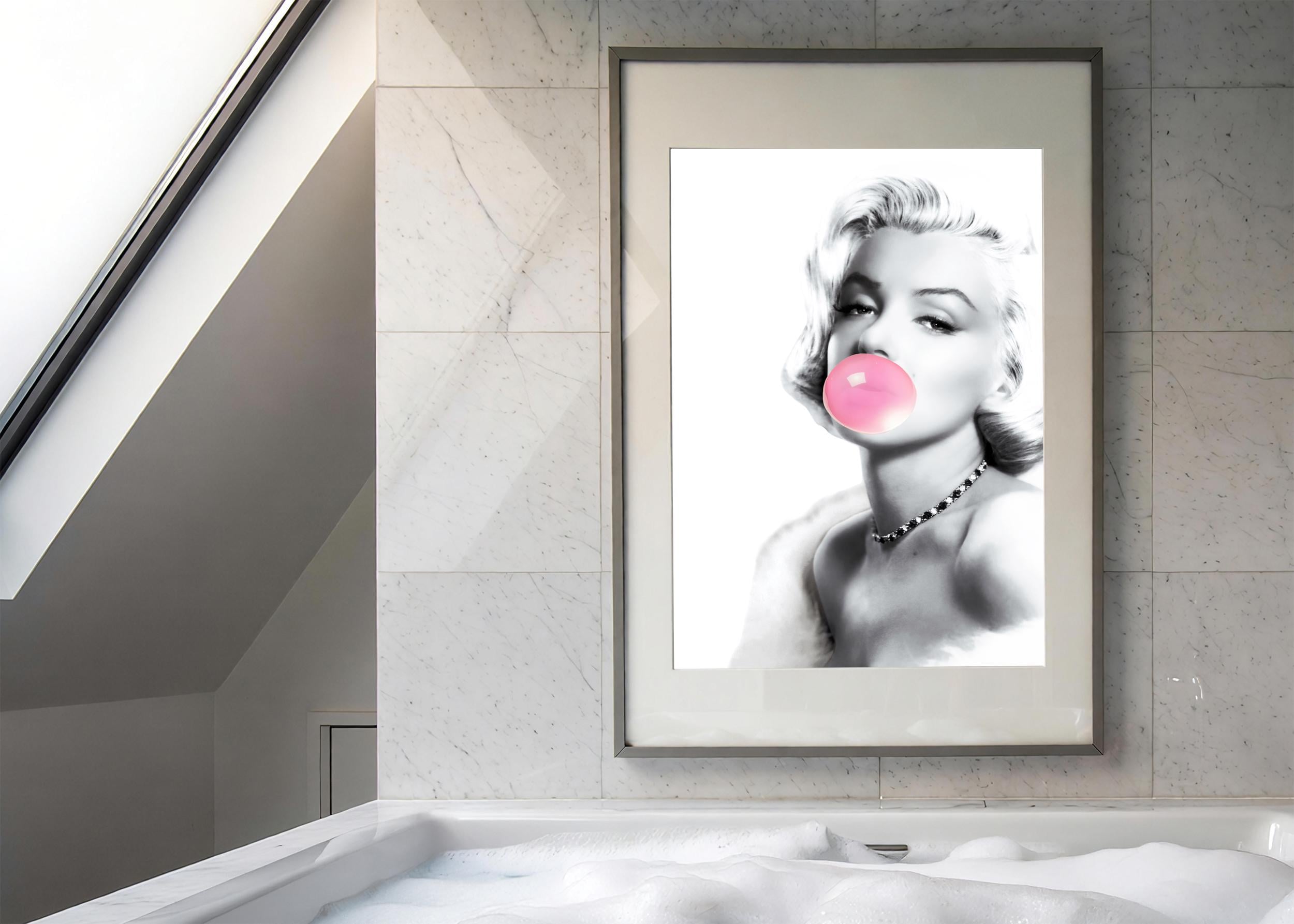 Framed artwork of a stylized portrait of Marilyn Monroe with a pink bubble gum bubble on a marble wall.