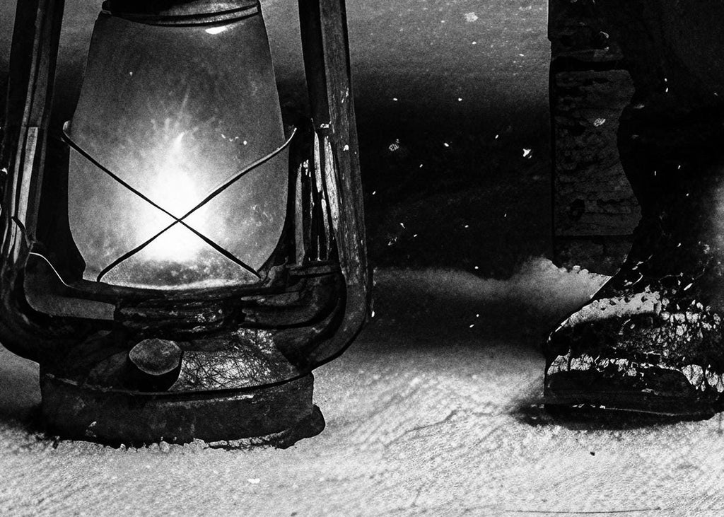 Vintage lantern with a lit candle on a snowy ground