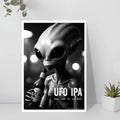 Poster of an alien holding a beer bottle with 'UFO IPA' text, framed on a wall.