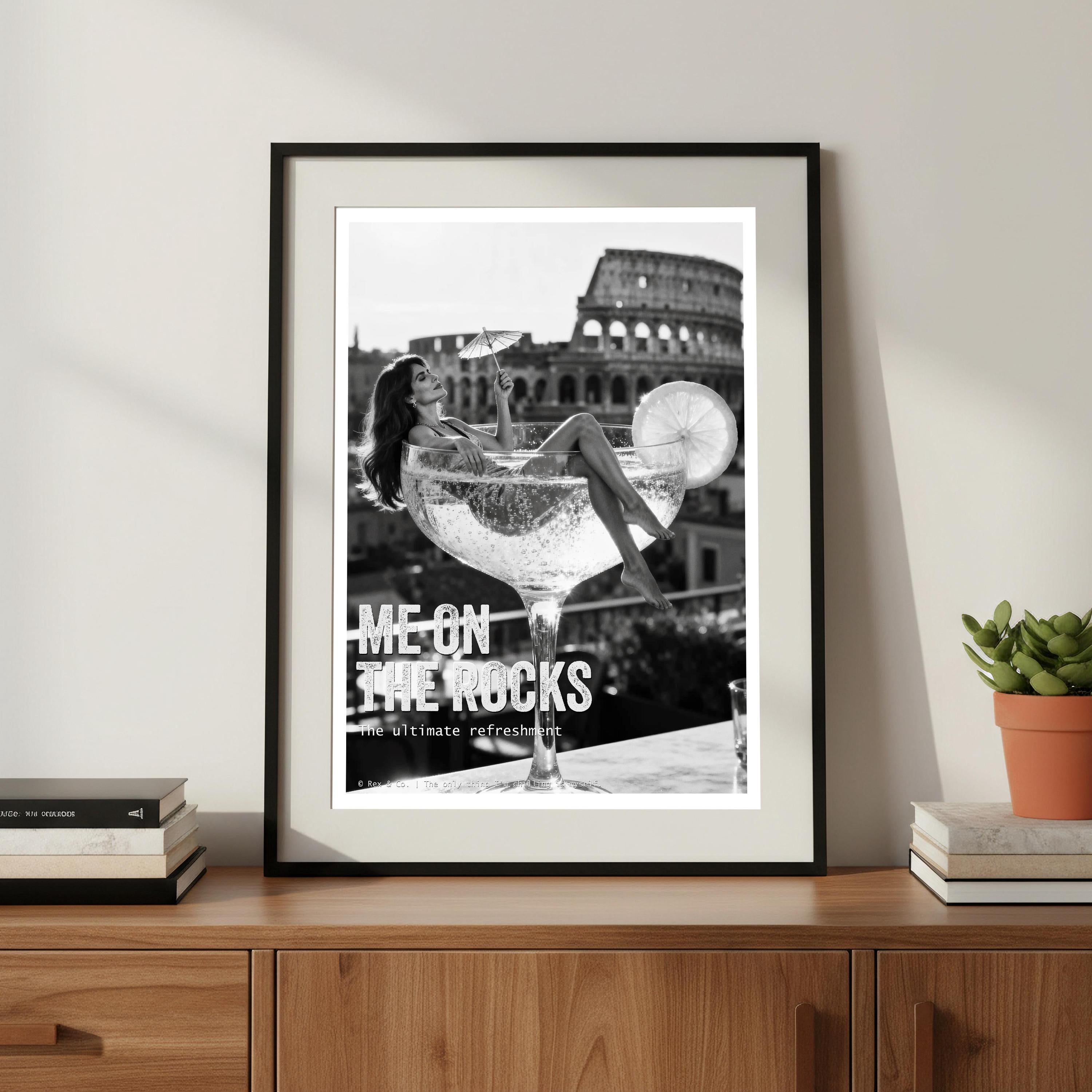 Framed artwork of a woman in a cocktail glass in front of the Colosseum, displayed on a wooden shelf.