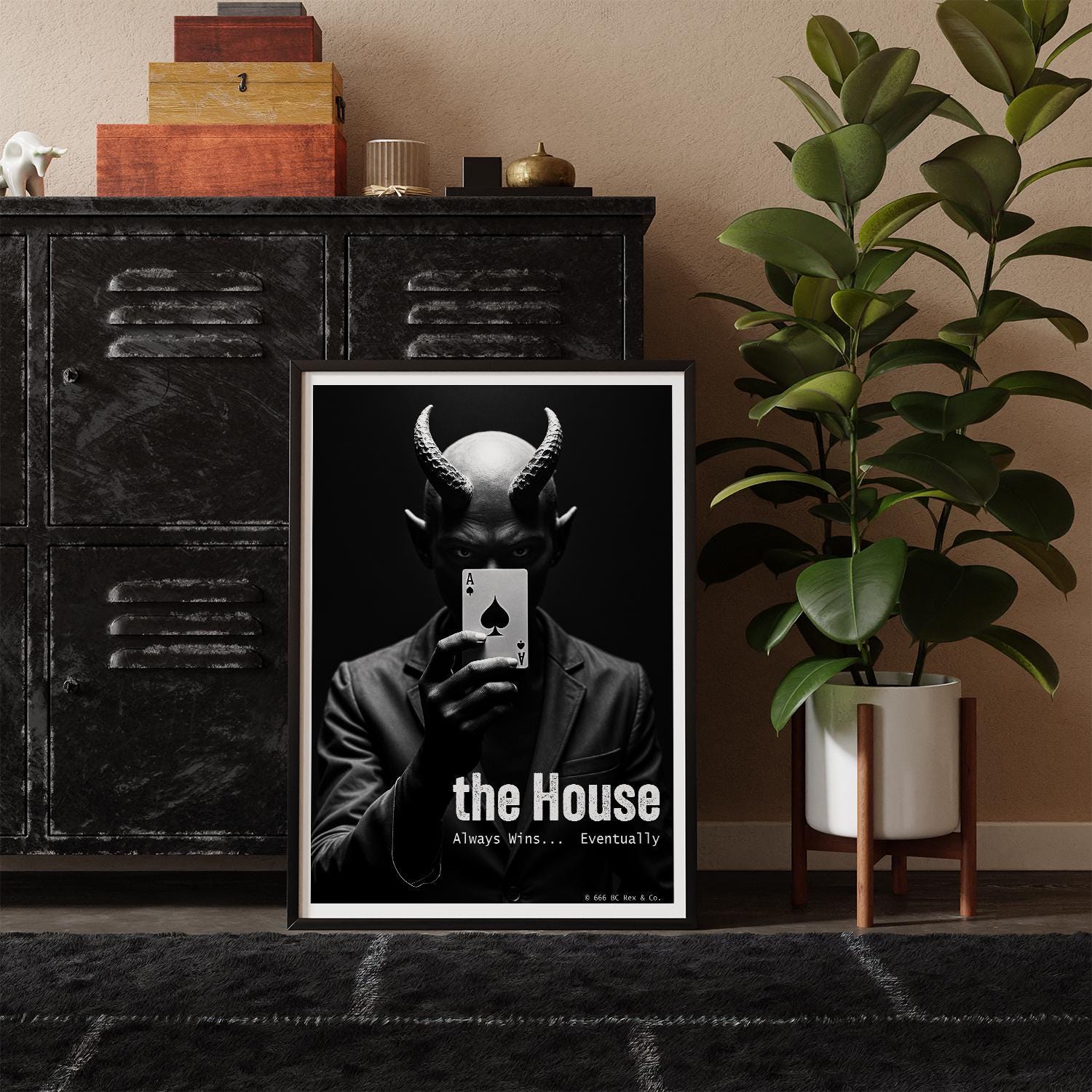 Framed poster with a stylized illustration of the Devil holding a card, placed against a shelf with decorative items and a plant.