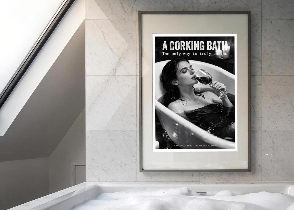 Framed poster of a woman in a bathtub with a glass of wine, displayed above a modern bathtub.